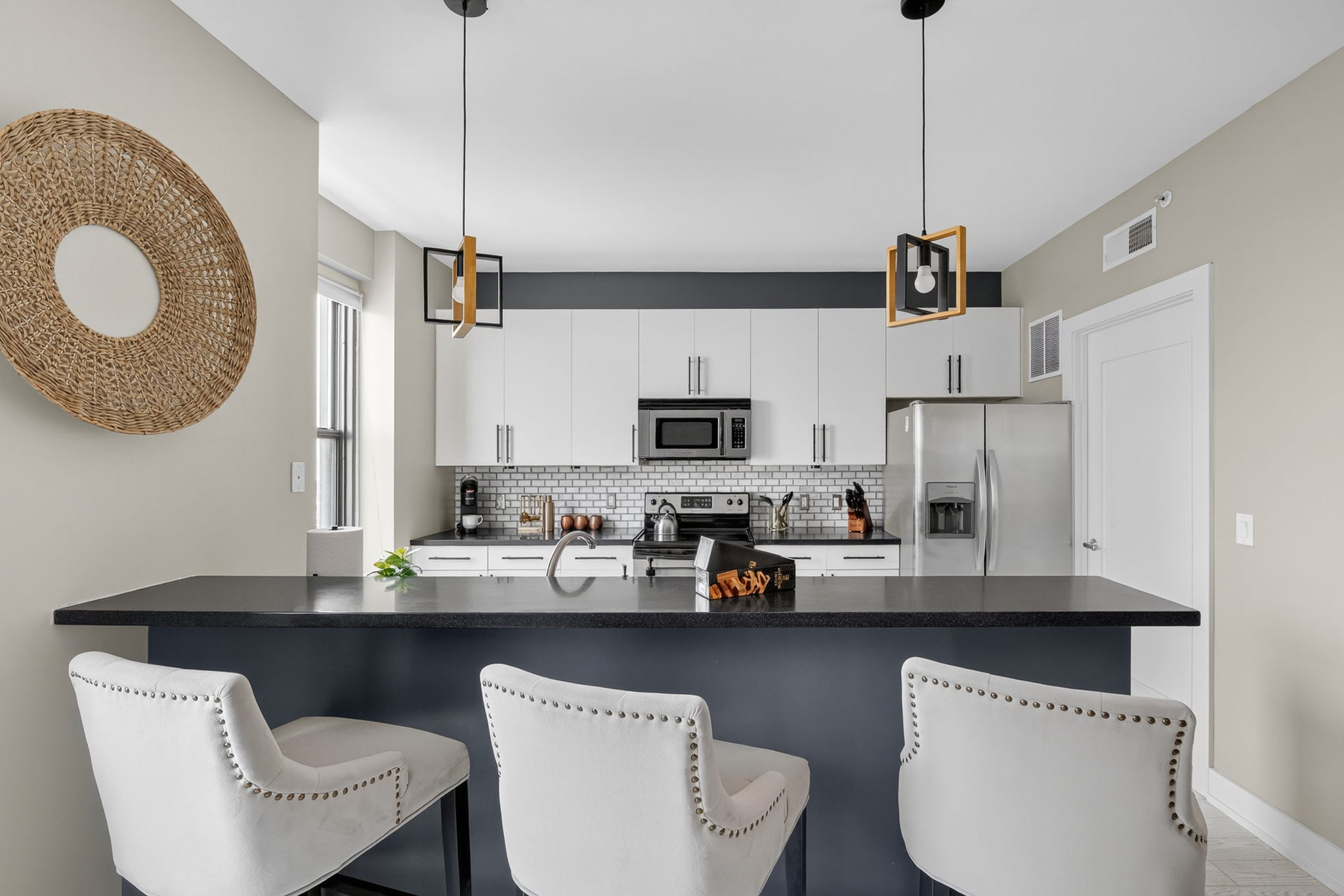 Fully stocked kitchen with stainless appliances, coffee maker, and sleek bar seating for four. Ideal for cooking, working remotely, or enjoying takeout with style.