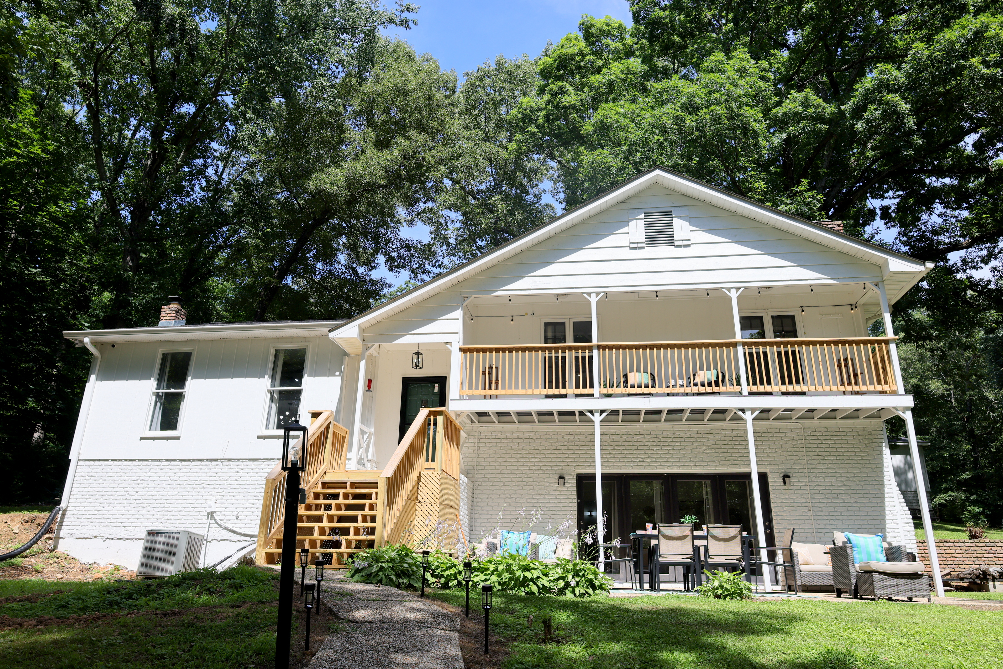 Exterior view of the lake house with spacious decks, outdoor seating, and wooded surroundings