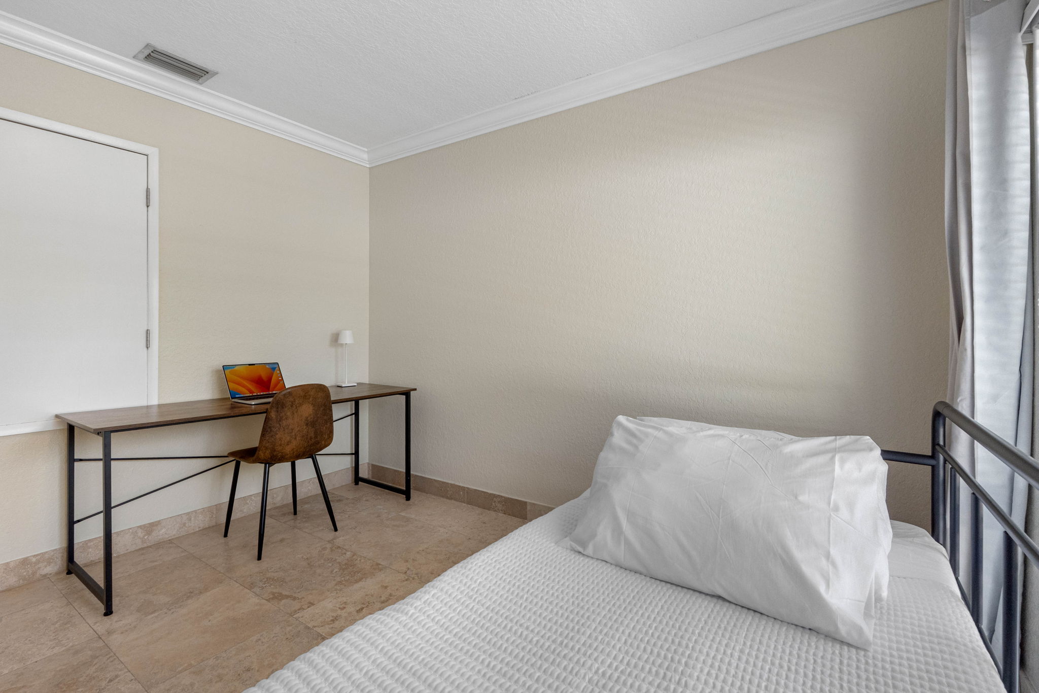 A sunny room offering both a comfortable daybed and a dedicated work desk, ideal for remote work or study.