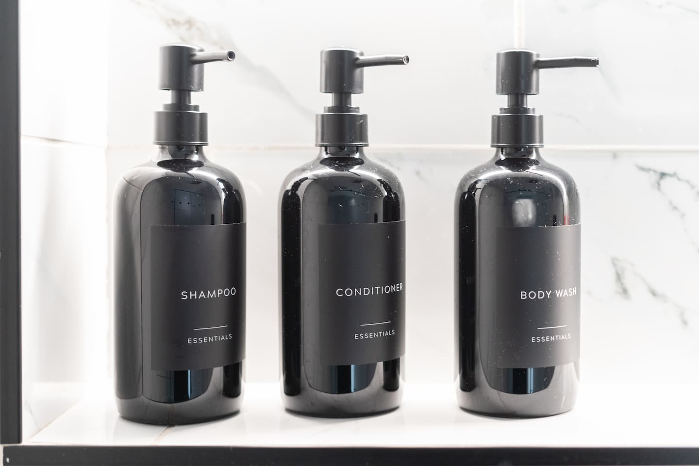 Minimalist black pump bottles for shampoo, conditioner, and body wash.

