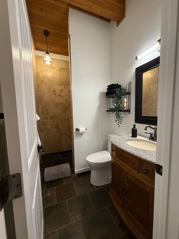 Mountain-lodge shower - slate  travertine shower, vanity with deep drawers for bathroom items, live edge shelves for convenience and comfort height for those sore quads. 