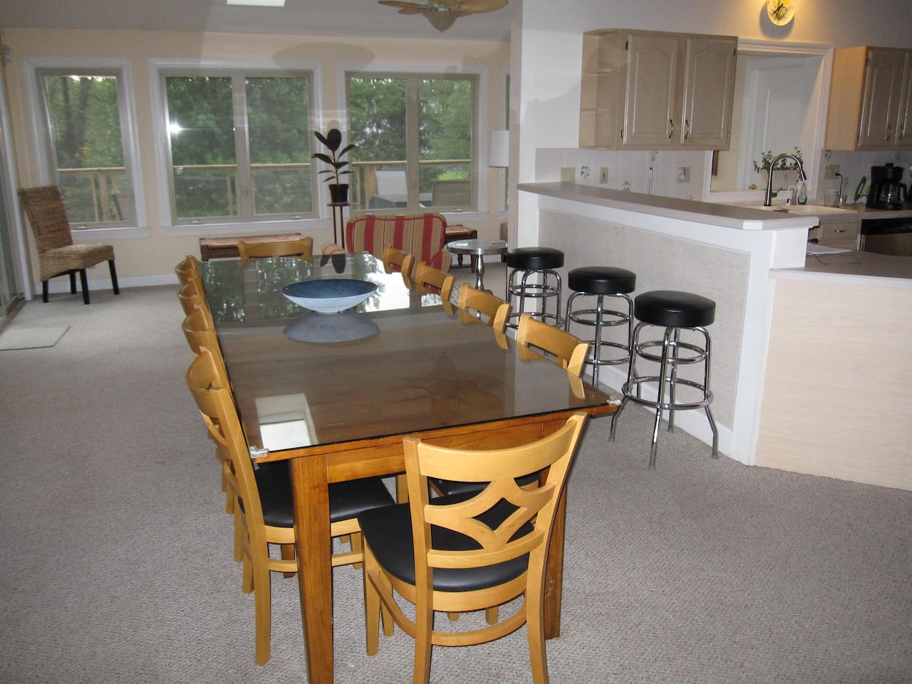 View of the dining table which has 10 chairs and extra seating can be accommodated using the benches in the sunroom.  Three bar stools on the right face the kitchen.  Open floor plan.