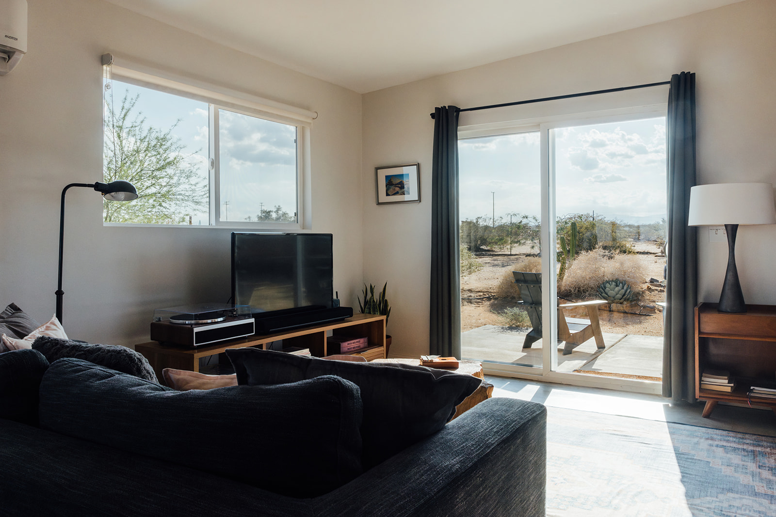 Stylish living room with cozy seating, eclectic decor, and sliding glass doors framing the desert landscape.