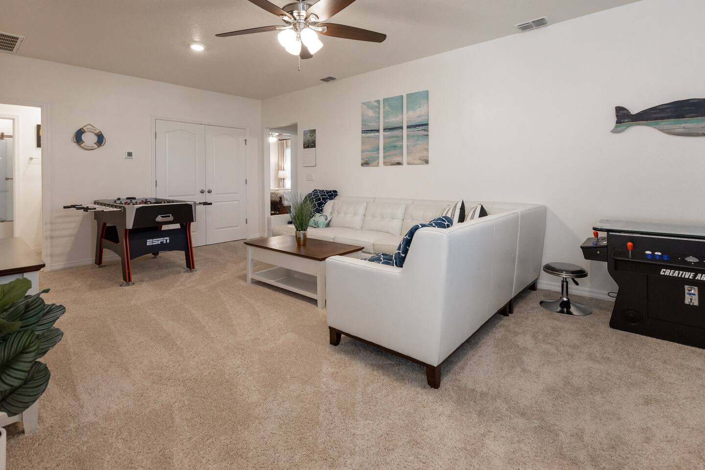Upstairs lounge area with couch, 75in smart TV, overhead fan, air hockey table, foosball table and two player arcade game with thousands of games. 