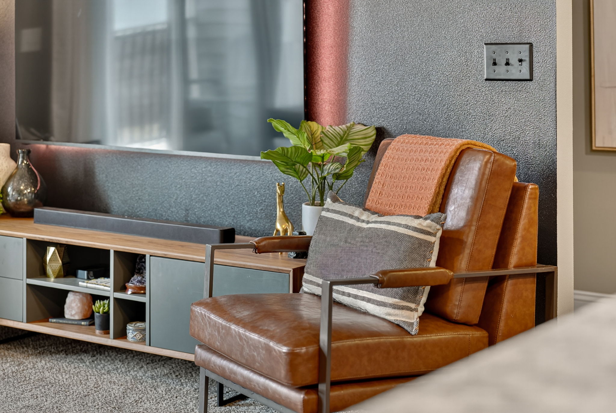 Modern media console and leather chair with décor accents. Custom touches transform this space into a chic condo-inspired retreat.