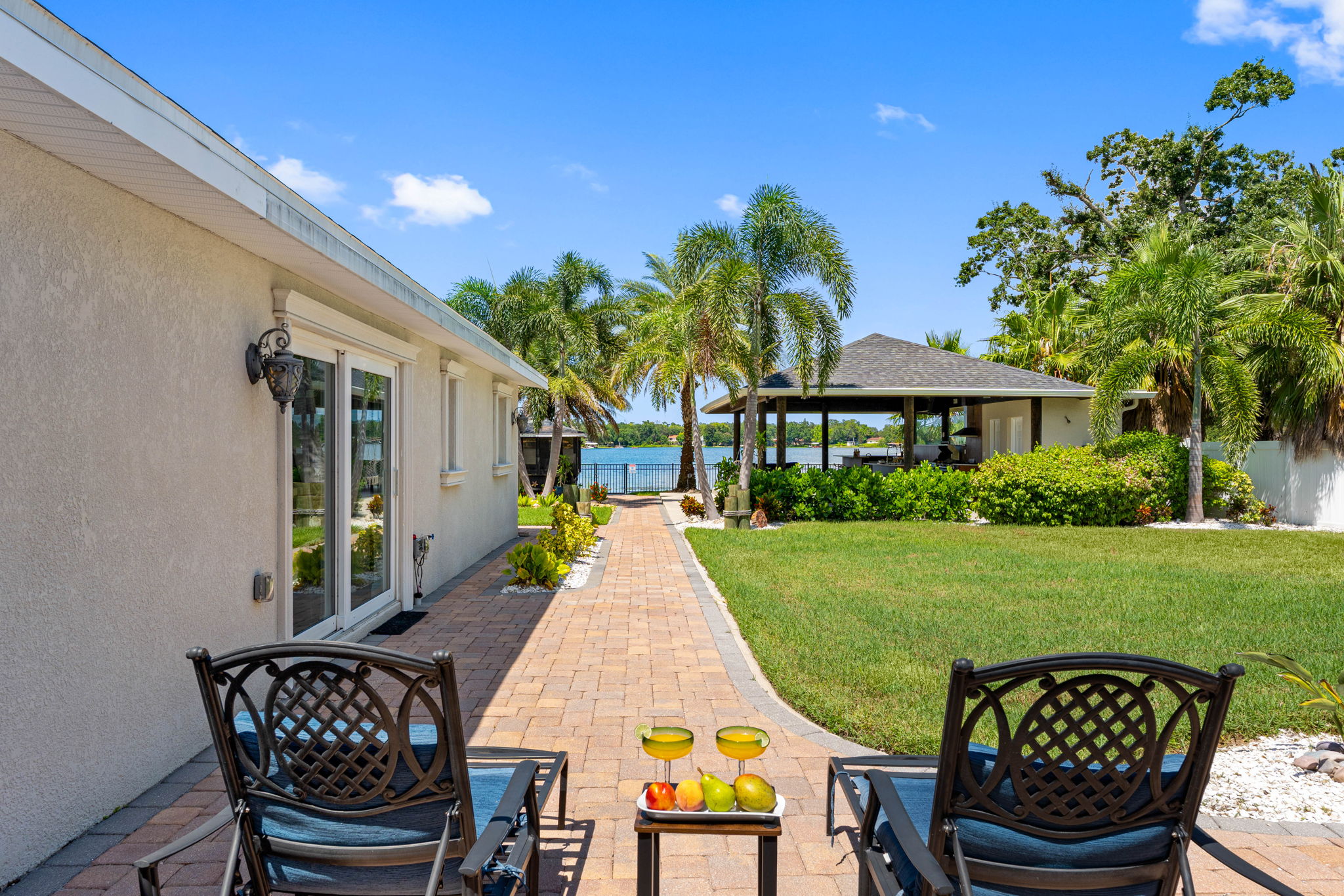 A private space with comfortable seating overlooks a vibrant lawn, framed by palm trees and coastal-inspired landscaping.