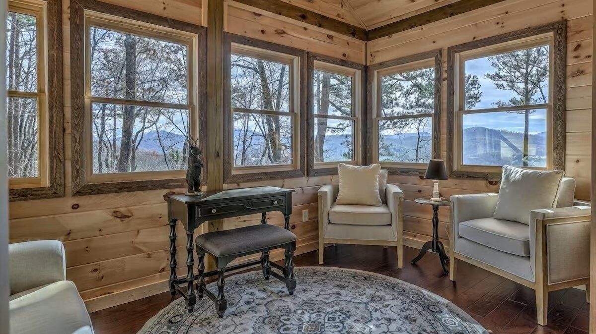 Sunlit sitting room with panoramic windows and mountain views - an ideal spot to read, relax, or work remotely.