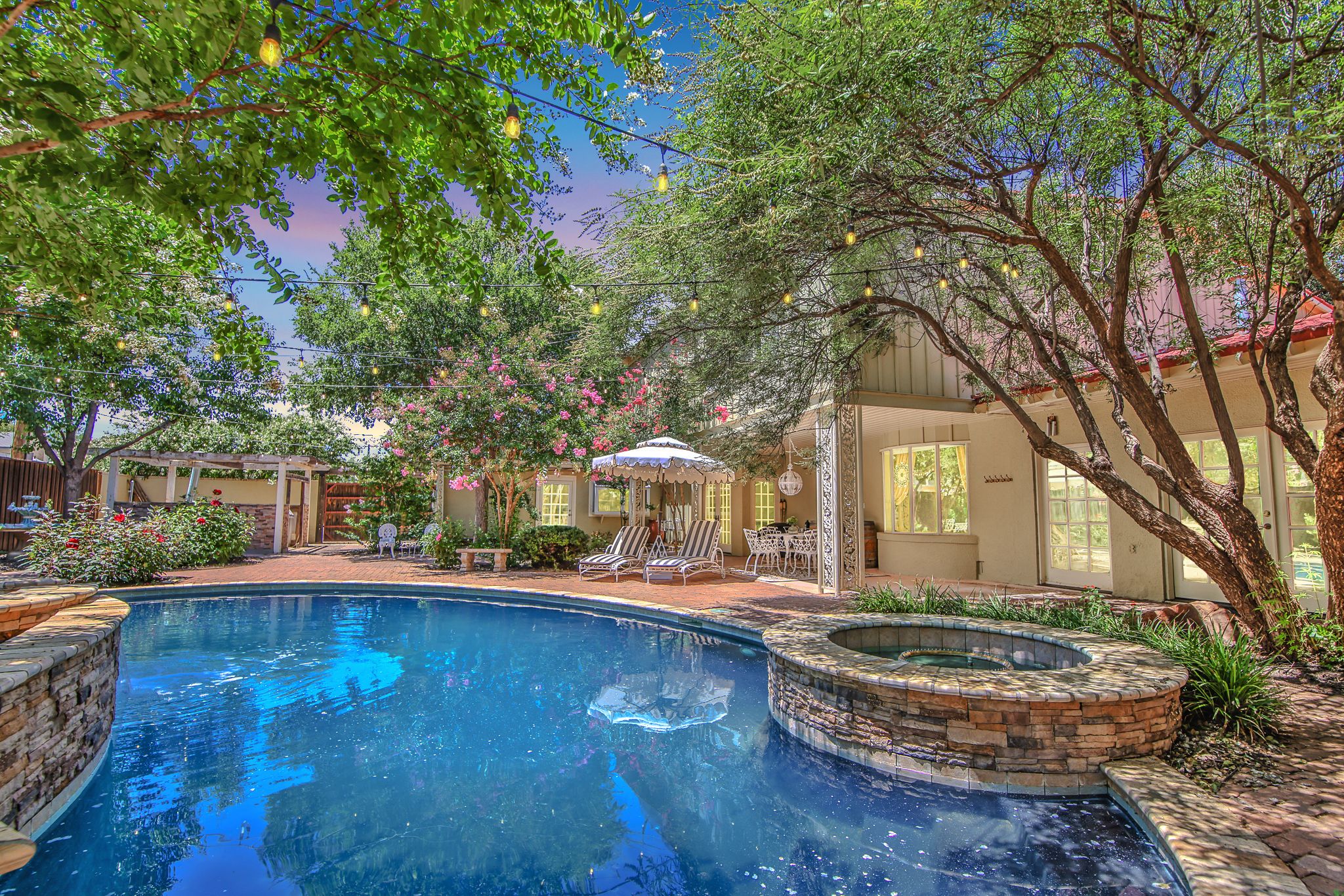 Cool off in style in this lavish outdoor oasis, featuring a sparkling black pool surrounded by lush foliage and elegant loungers.