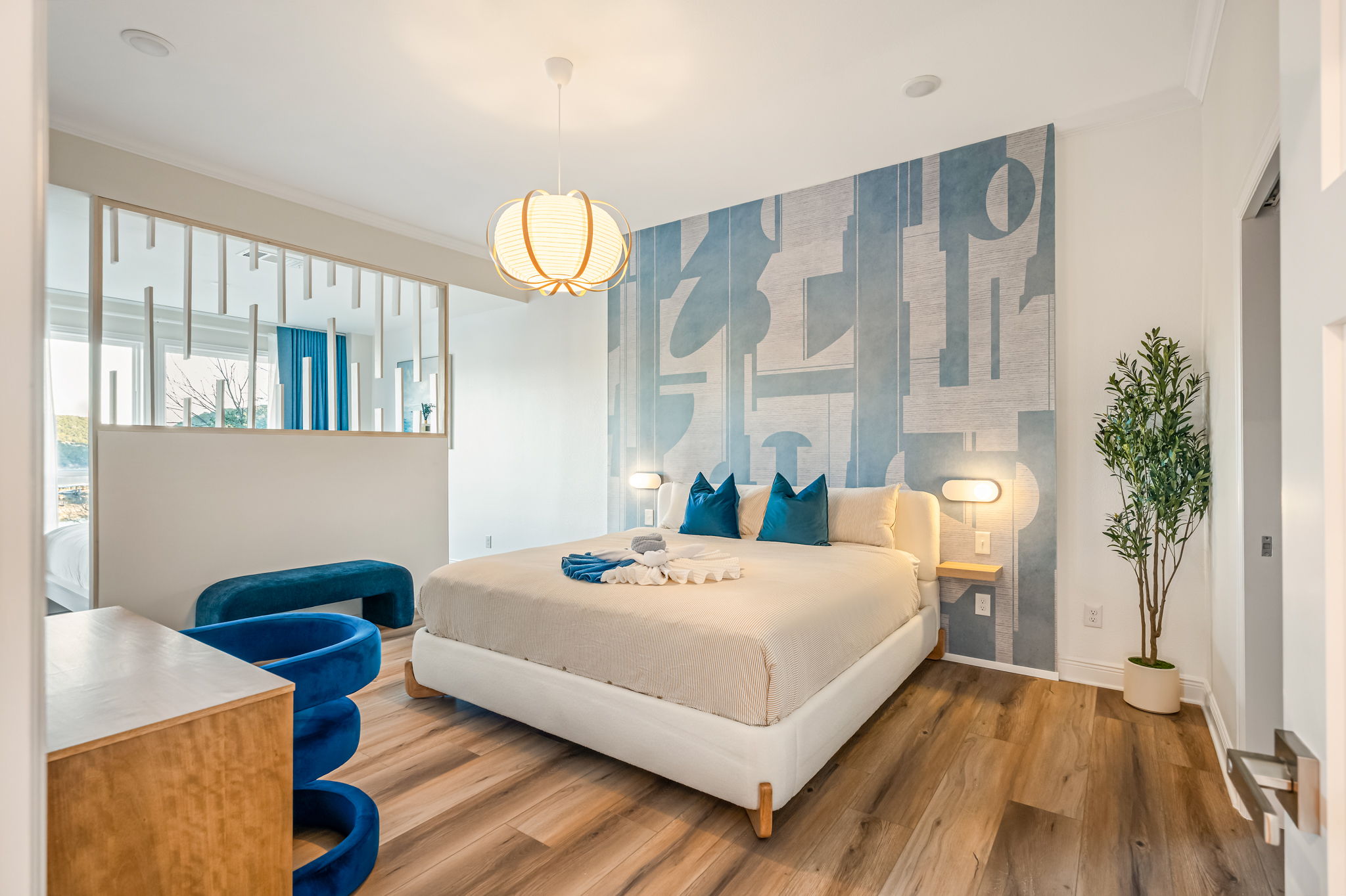 Spacious primary bedroom with plush king bed, stylish accent wall, and bright natural light.