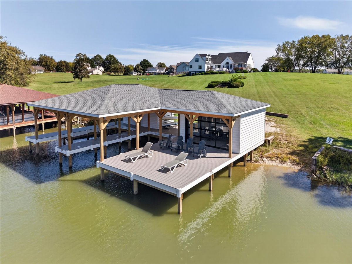 Waterside view of the boathouse with covered slips and shoreline lounging area.