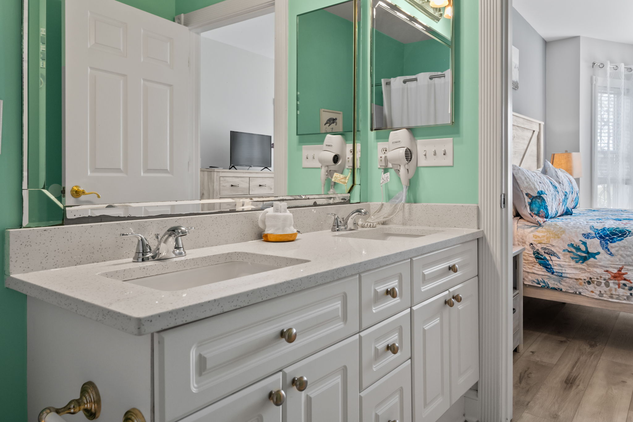 An attached bathroom featuring a sleek mirror, two faucets, and a white storage cabinet—combining modern design and practicality for a clean and organized space.