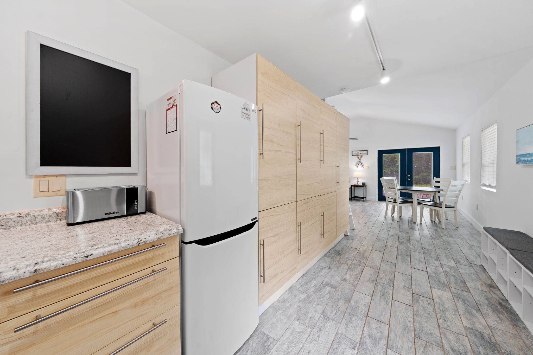 Open layout with a fridge and plenty of cabinet space connecting the kitchen, dining, and living spaces