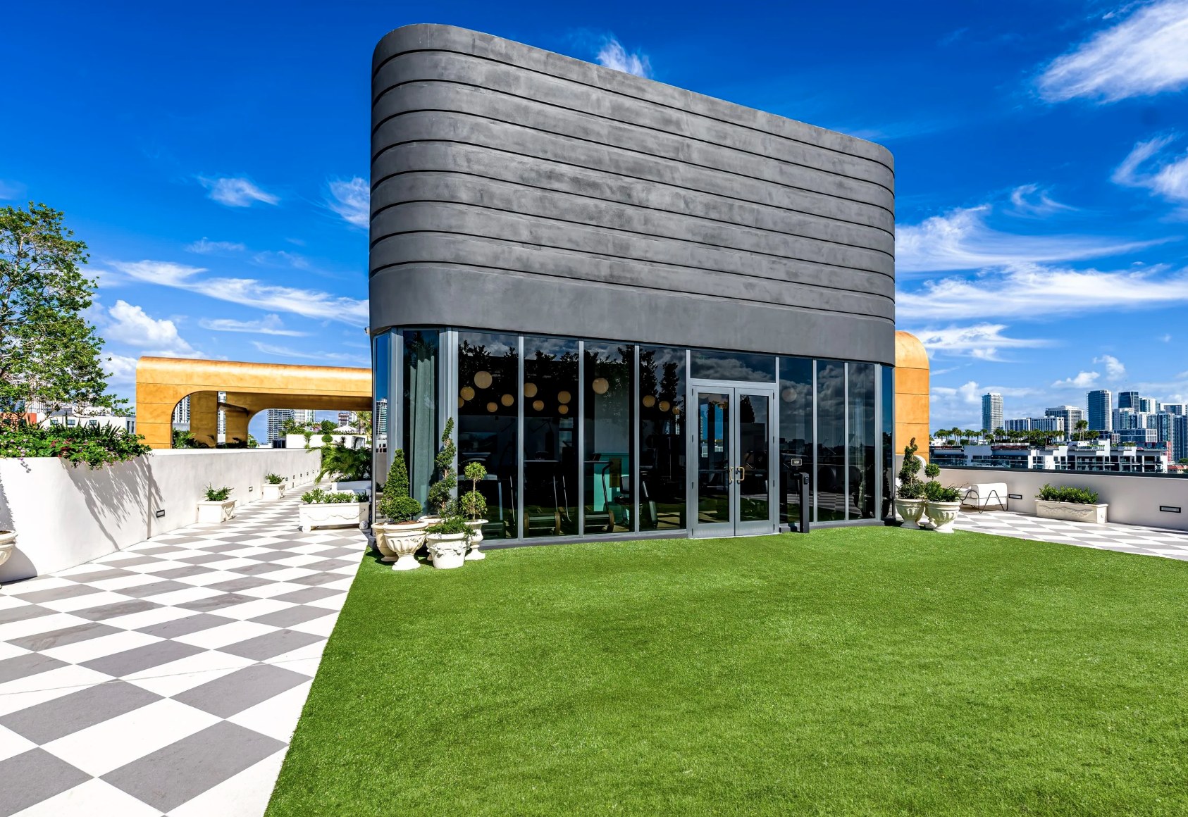Rooftop observation lounge — turf deck and floor-to-ceiling skyline glass room