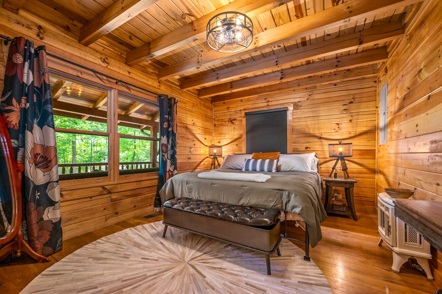 Second bedroom features a king-sized bed, warm ambient lighting, and peaceful wooded views.