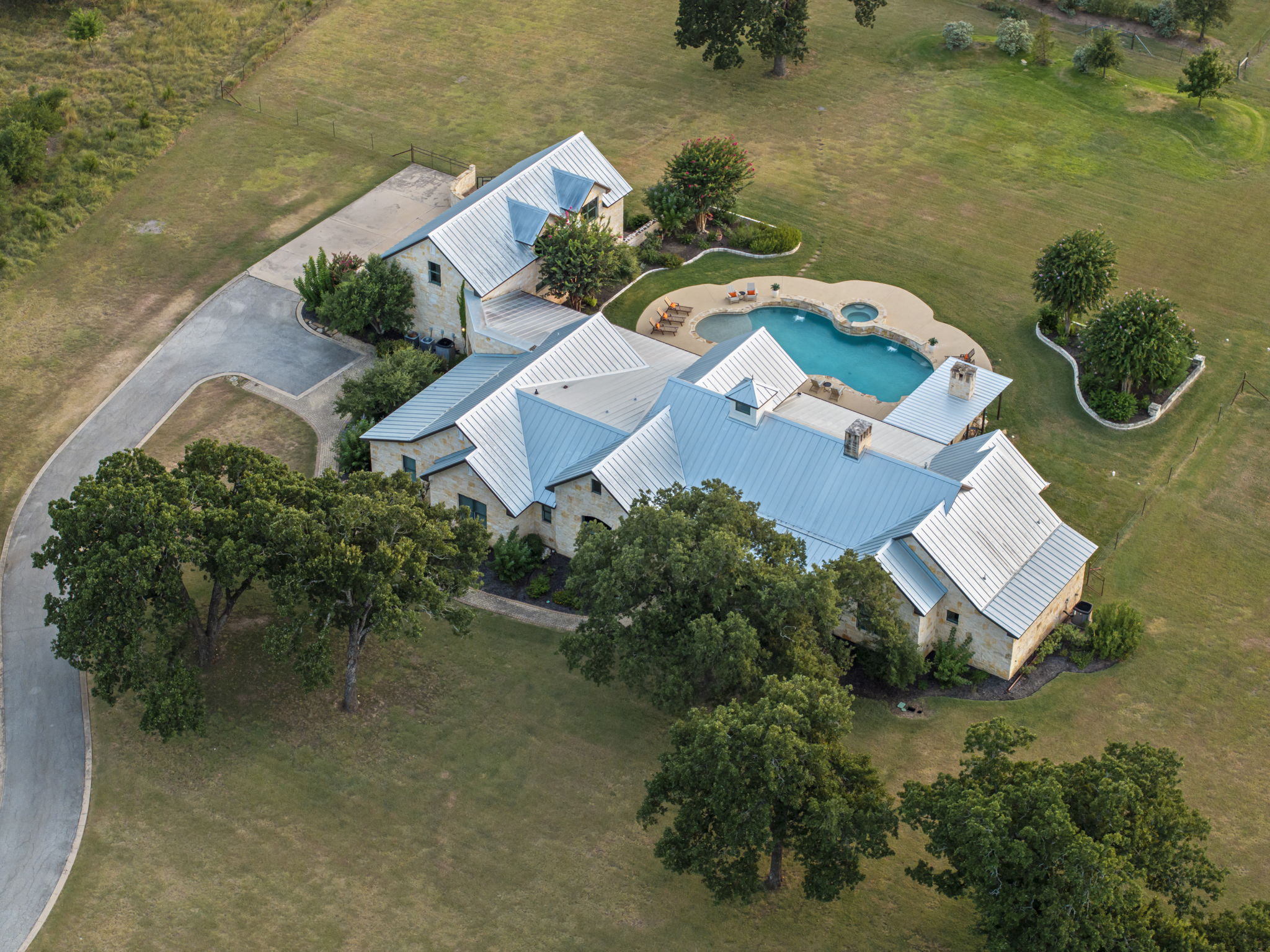 Bird's-eye perspective of a beautiful home and its expansive grounds, featuring a sparkling swimming pool and hot tub.