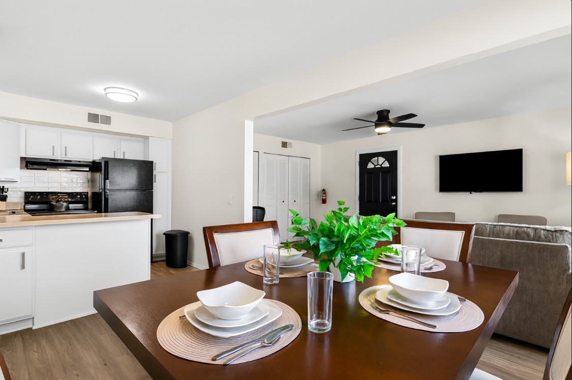 Bright open-concept dining and living space featuring a modern kitchen, cozy seating area with TV, and a stylish dining table setup—perfect for gathering and entertaining.
