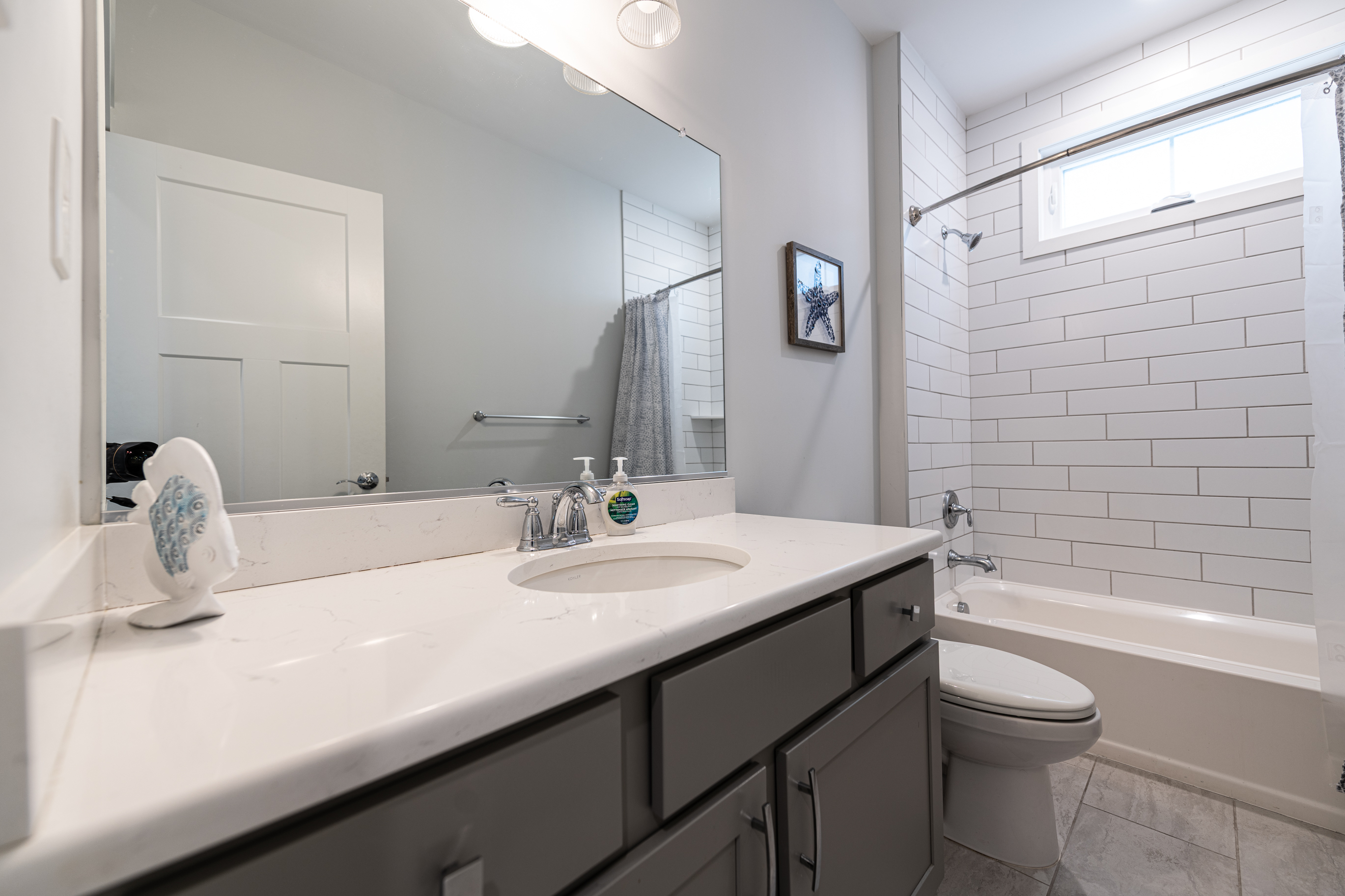 Hall bath w/ double vanity sinks and subway tiled shower/bath combo
