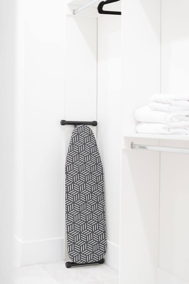 Closet space featuring an ironing board and neatly folded fresh linens.