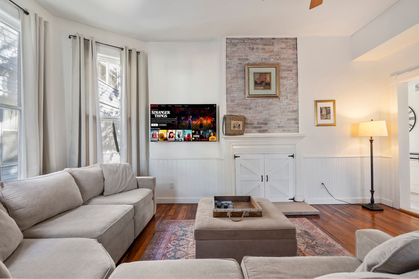 Spacious living room with original hardwood floors and large windows — light-filled and inviting