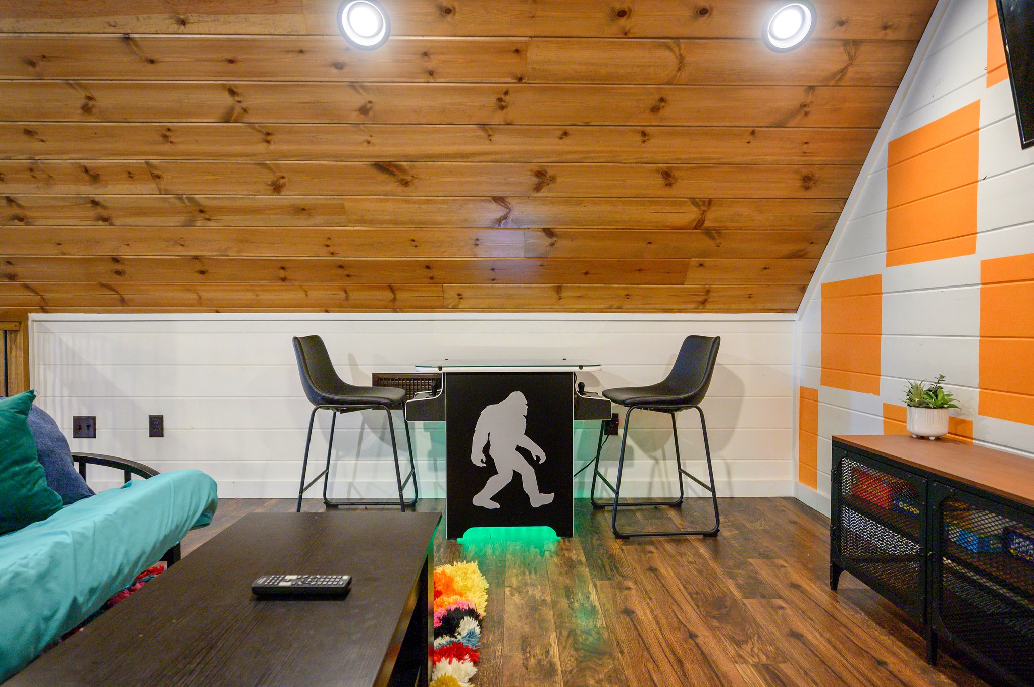 Disco Cowboy | Game loft with air hockey, Xbox and lounge seating. A twin daybed and trundle replaced the old futon; the cabin maximum remains 10 guests, with two king beds and six twin bunks as the advertised sleeping setup.
