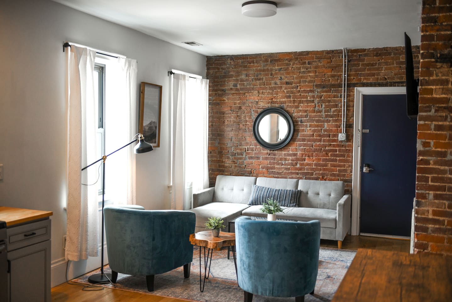 Bathed in natural light, this vibrant space offers a stylish L-shaped sofa, a sleek coffee table, and a cozy setup that blends comfort with modern charm.