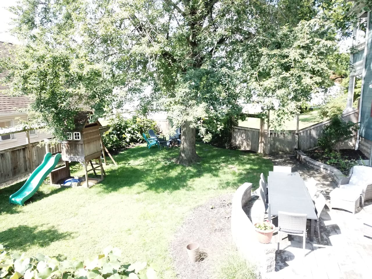 Private, fenced yard offers large dining table, seating area, playset, firepit, gas grill and room for yard games.
