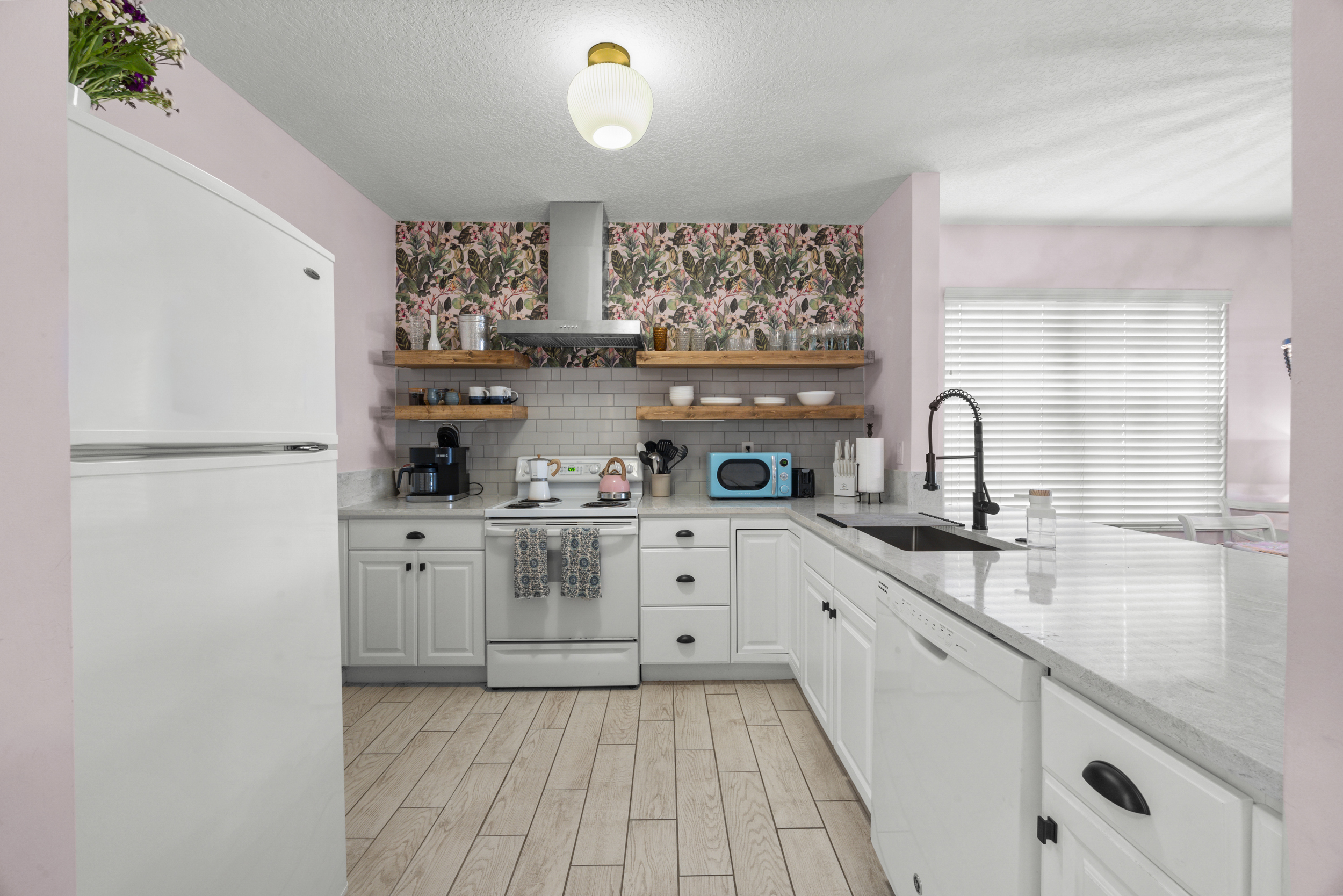 Bright, modern kitchen with white cabinetry, floral accents, and open shelving for a fresh coastal feel.