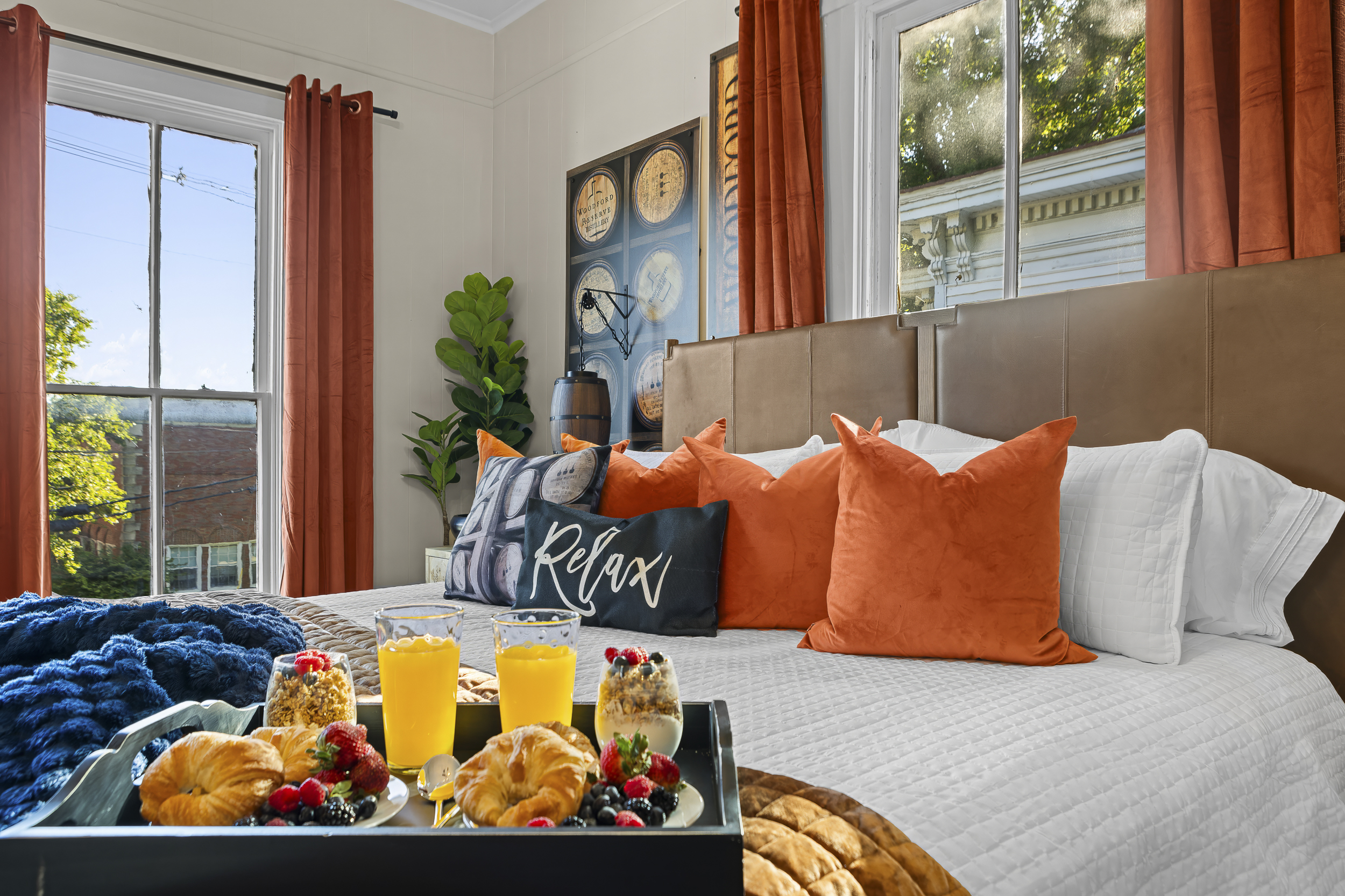 Natural light fills the Woodford Reserve Room, highlighting the orange drapes, plush king bed, and the luxury of having nowhere to rush off to.