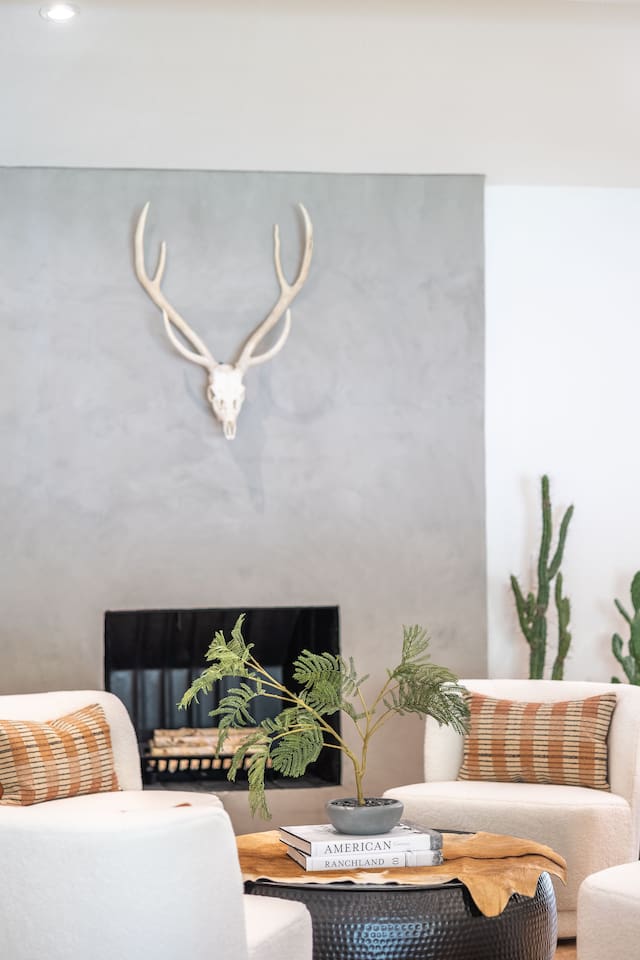 Fireplace seating area with cozy accent chairs, sculptural coffee table, and warm textures creating an inviting conversation space.