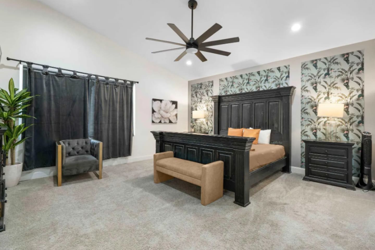 Luxe bedroom with statement black bed frame, botanical wallpaper, and spa-like seating area.