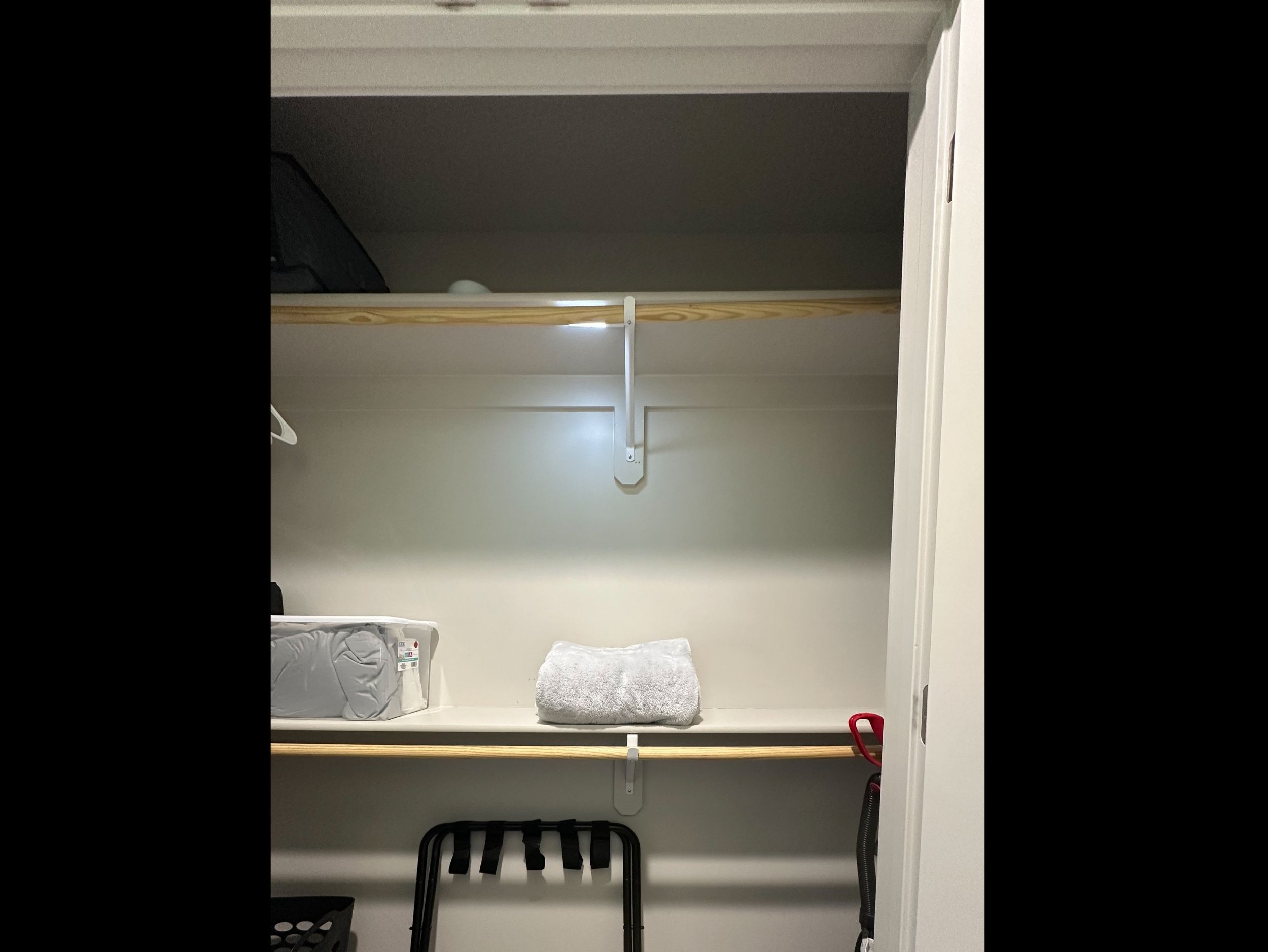 Generous primary closet stocked with extra linens and blankets, plus luggage rack, laundry basket, and vacuum for convenient extended stays.