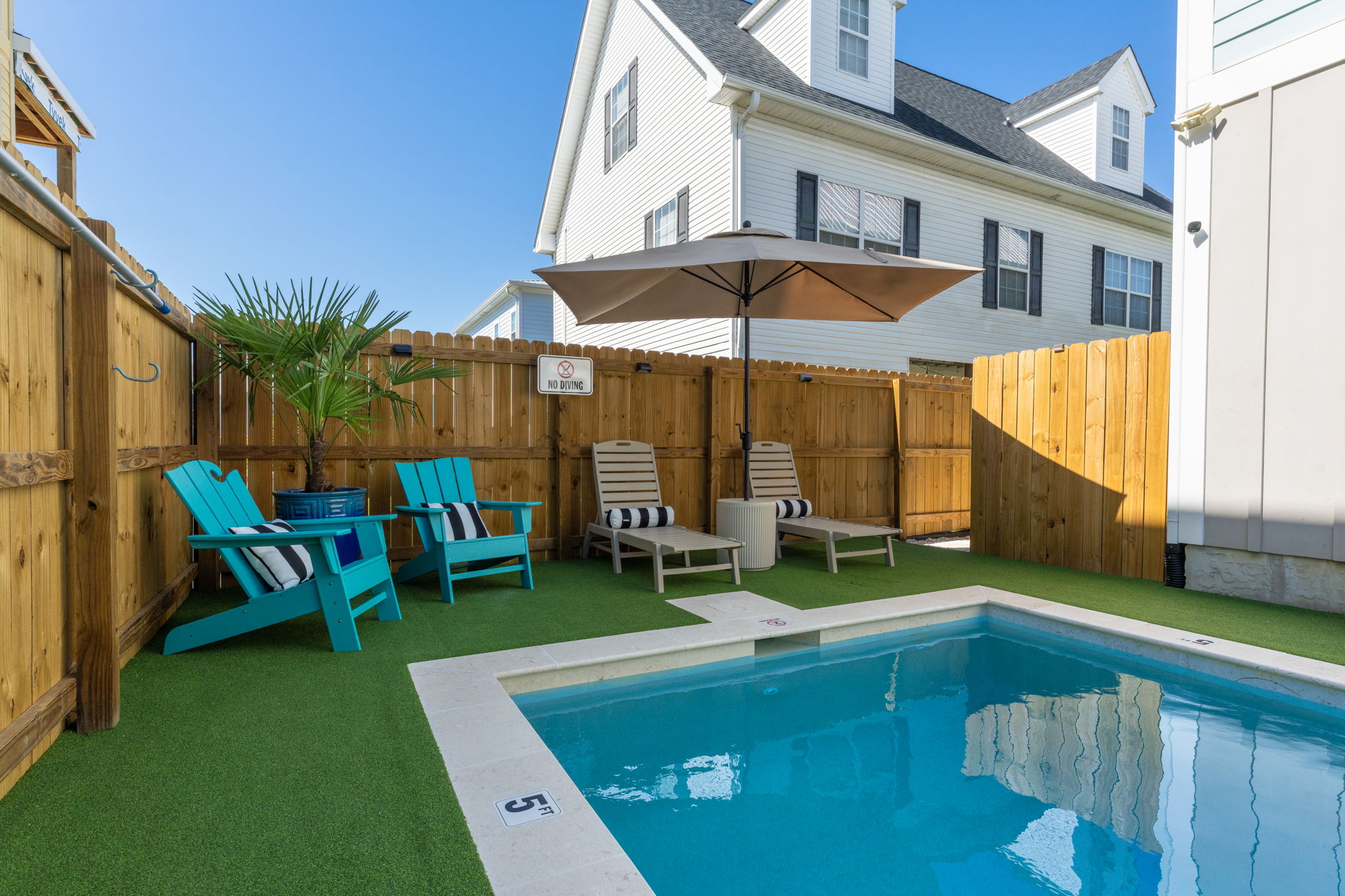 Fully fenced private pool with loungers, shade, and seating.