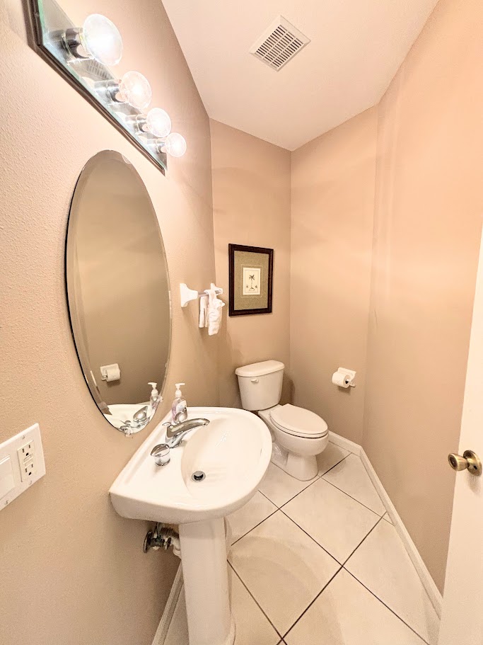 Convenient half bathroom with pedestal sink, tile flooring, and clean, neutral finishes.