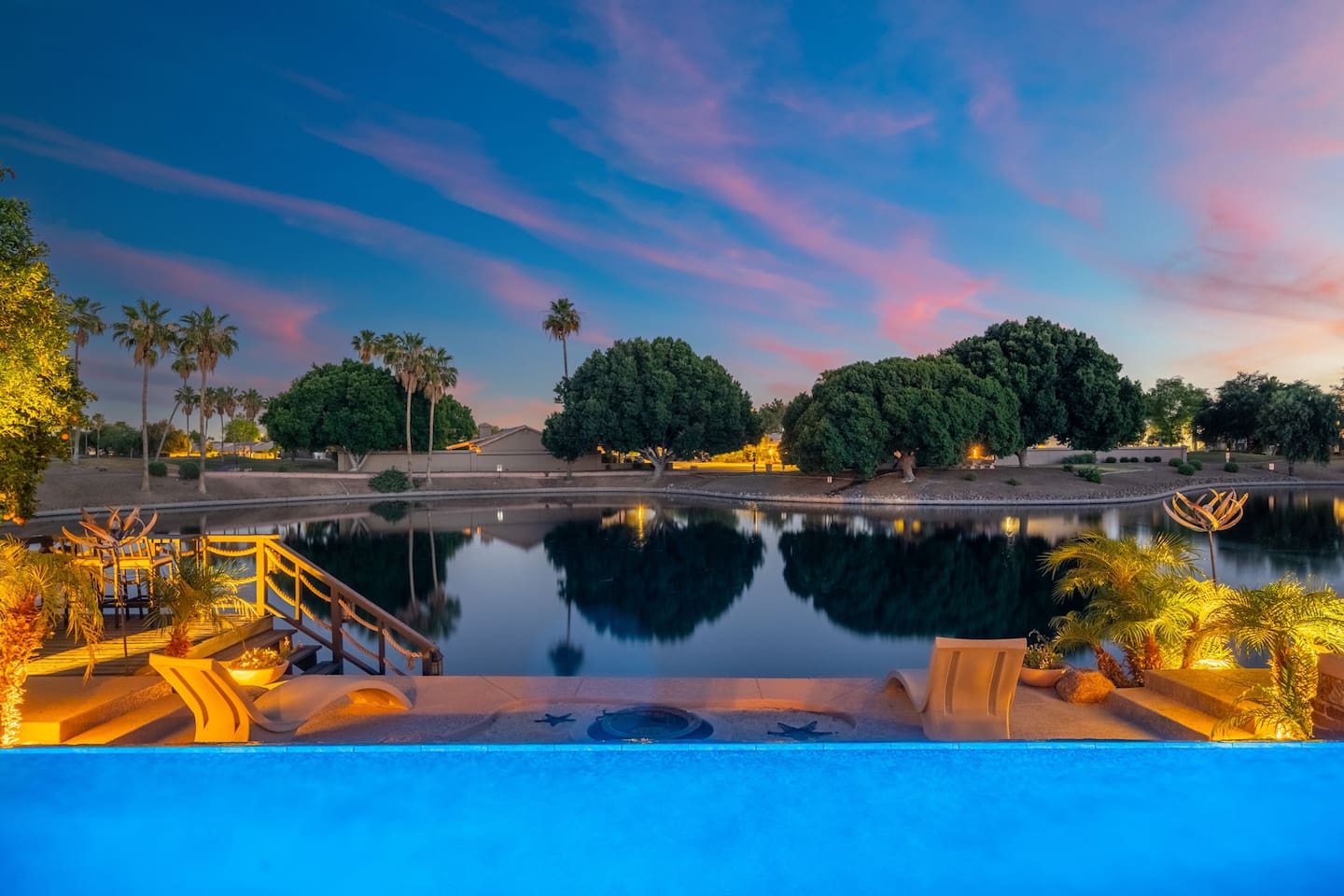 From the pool's edge, the lake stretches out under a blazing sunset sky — a view so stunning it almost doesn't feel real. This is the backyard you've always dreamed of.