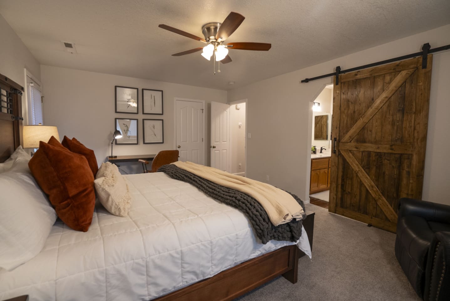 Spacious primary bedroom with a large king bed, work desk, closet storage, and access to bathroom.