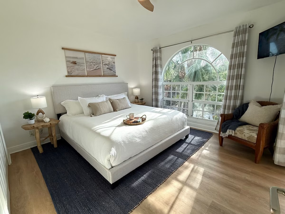 King size bed, oversized window provides views of the property's lush palm-lined paradise