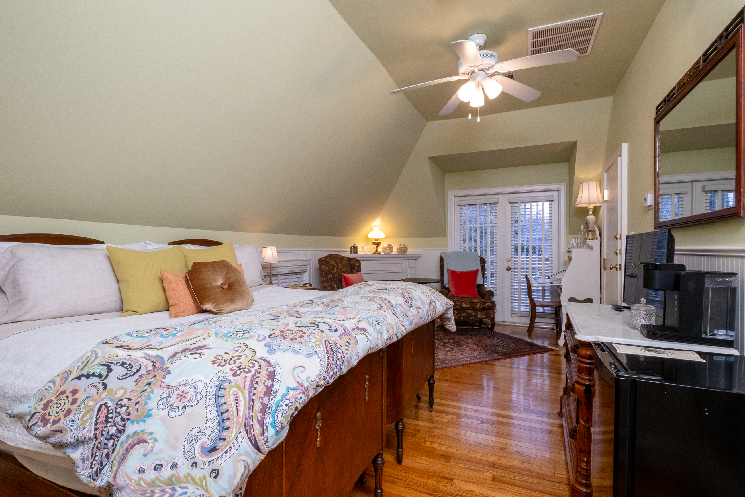 Wide bedroom view showcasing the sleeping area, ceiling fan, and thoughtfully arranged furnishings.