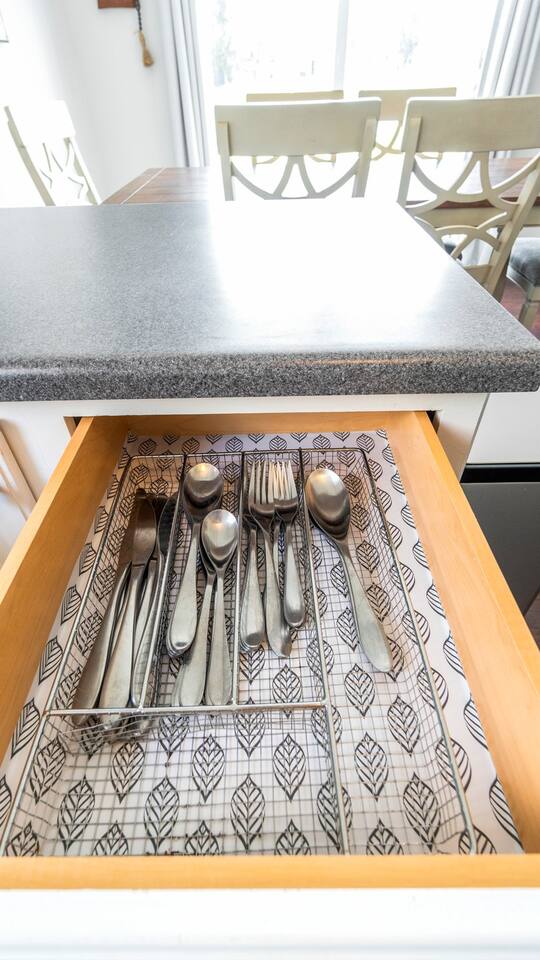 Stainless steel forks, knives, and spoons set neatly in a lined drawer for easy access during mealtime.