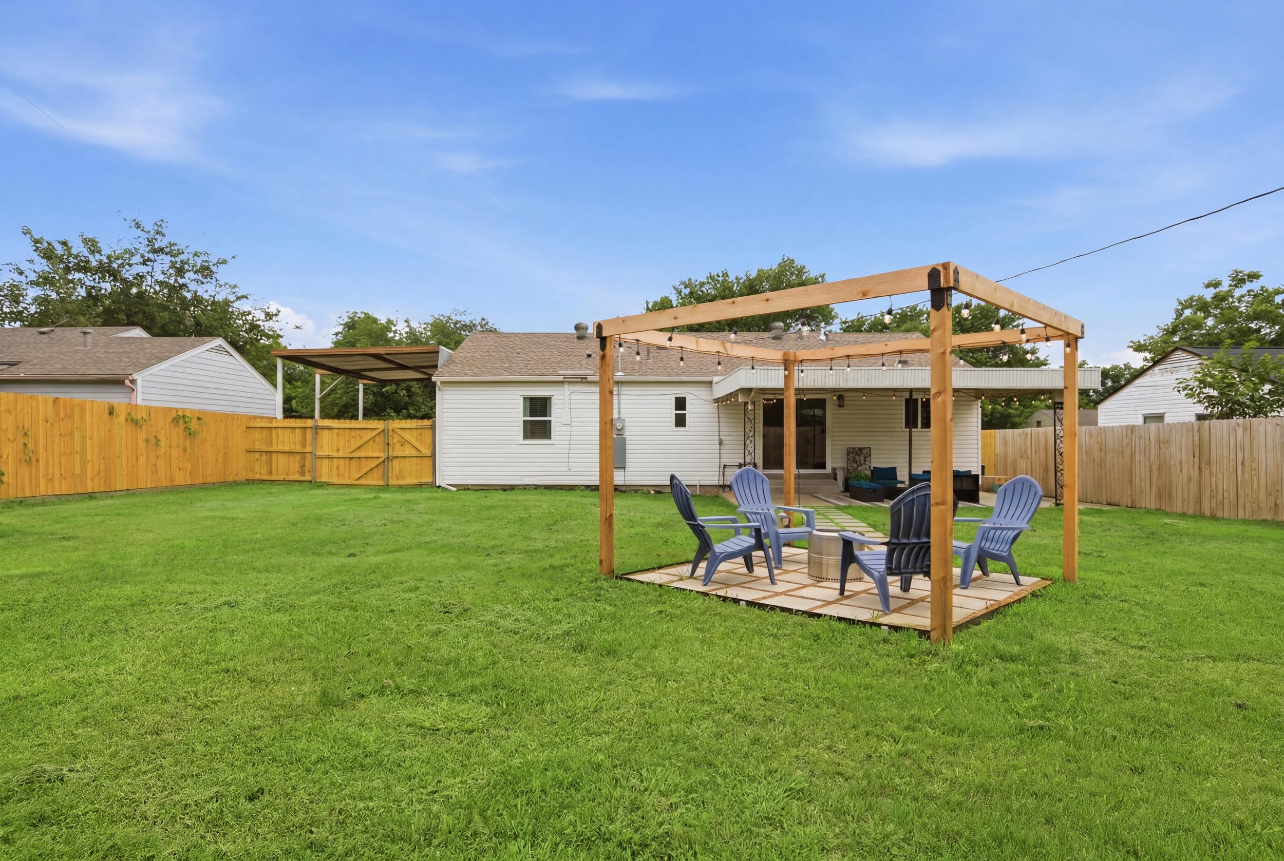 Wood Pergola with string lights, Outdoor Furniture and Fire Pit set on a stone patio. The perfect Arlington evening hangout after a long day exploring the Entertainment District.