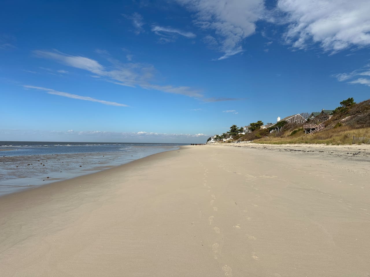 Explore miles of pristine coastline just moments away. This wide stretch of sandy beach features gentle waves and clear blue skies, providing the perfect backdrop for a relaxing day of sun, sand, and surf.