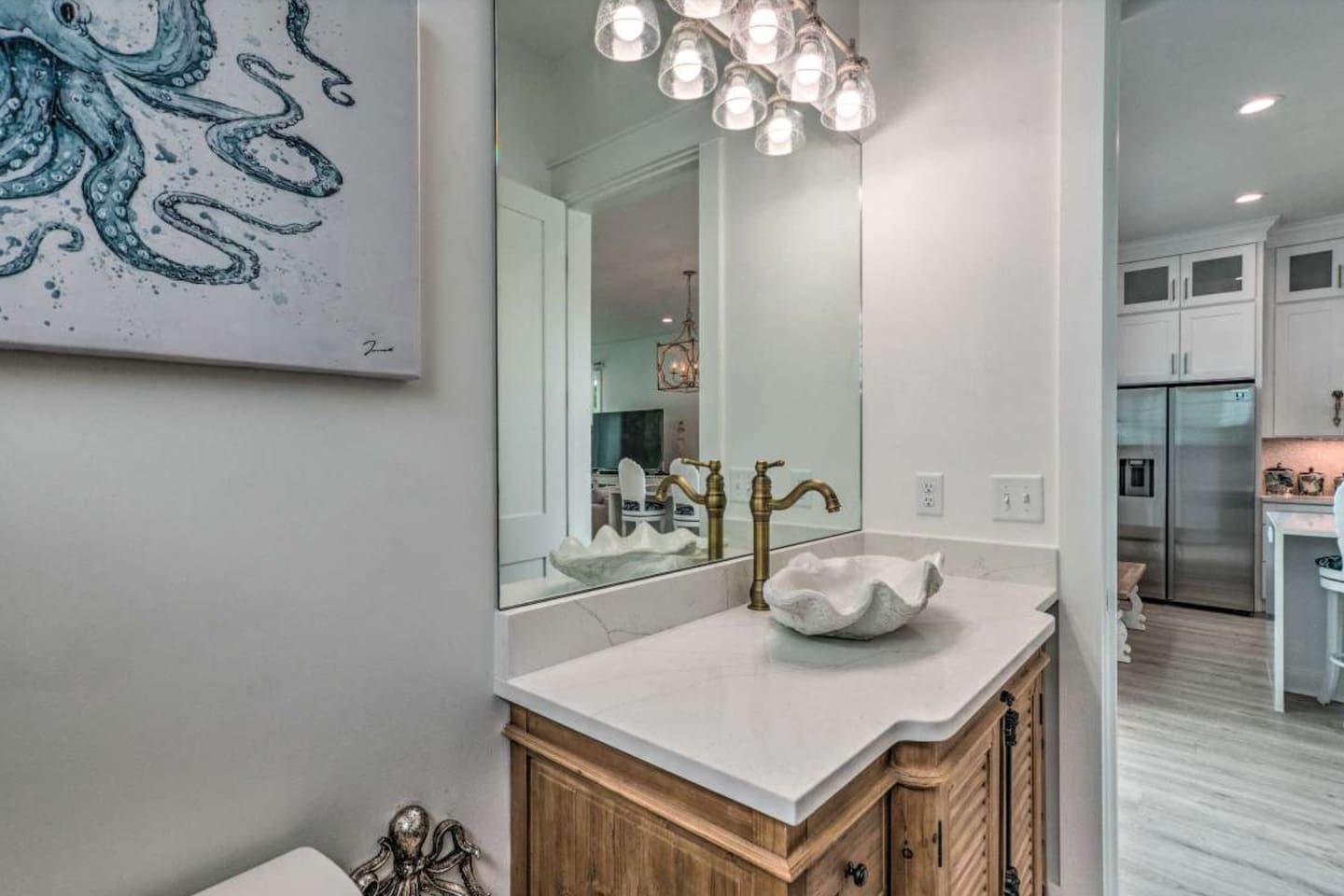 Main-floor half-bath beside kitchen and backyard, features a unique designer shell sink and bespoke 18th-century cabinetry , unique seahorse handles. Equipped with washer/dryer, iron, and beach towels—convenience meets 30A coastal style.