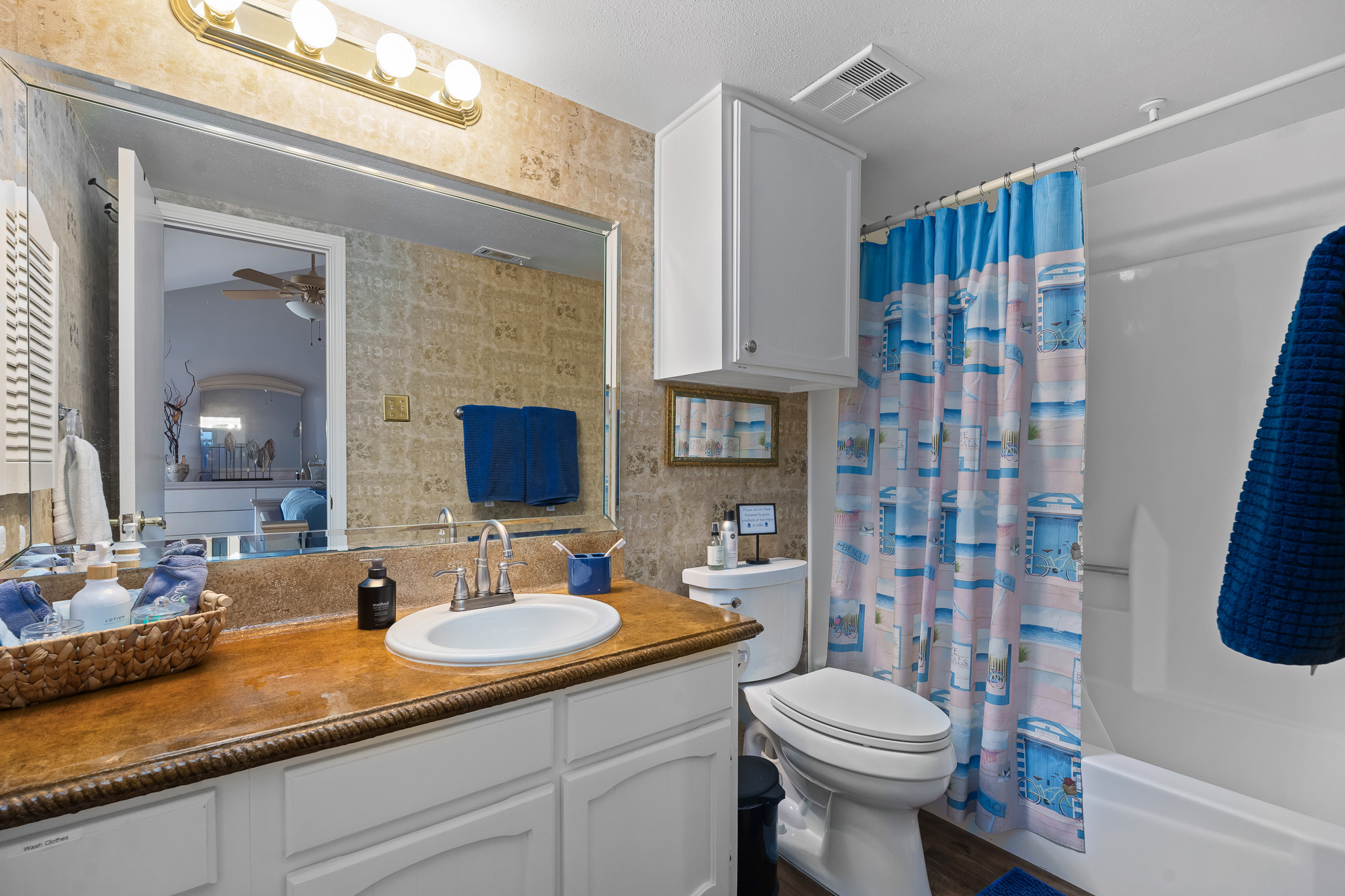The master bathroom features a clean and inviting space with a tub/shower combo, coastal-themed accents, fresh linens, and essential toiletries—all thoughtfully prepared for your stay.