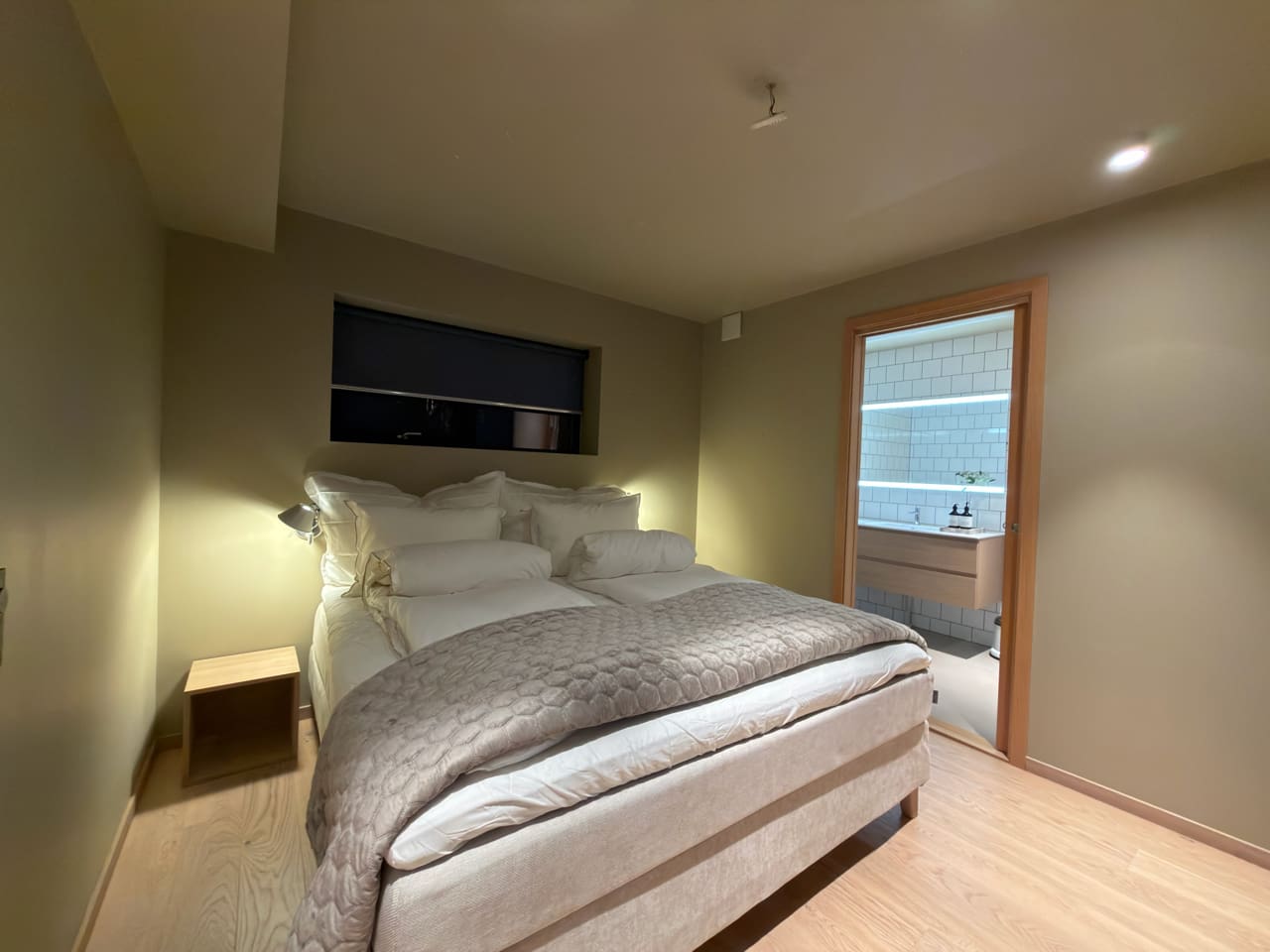Bedroom with big high end bed and enclosed bathroom with bathtub