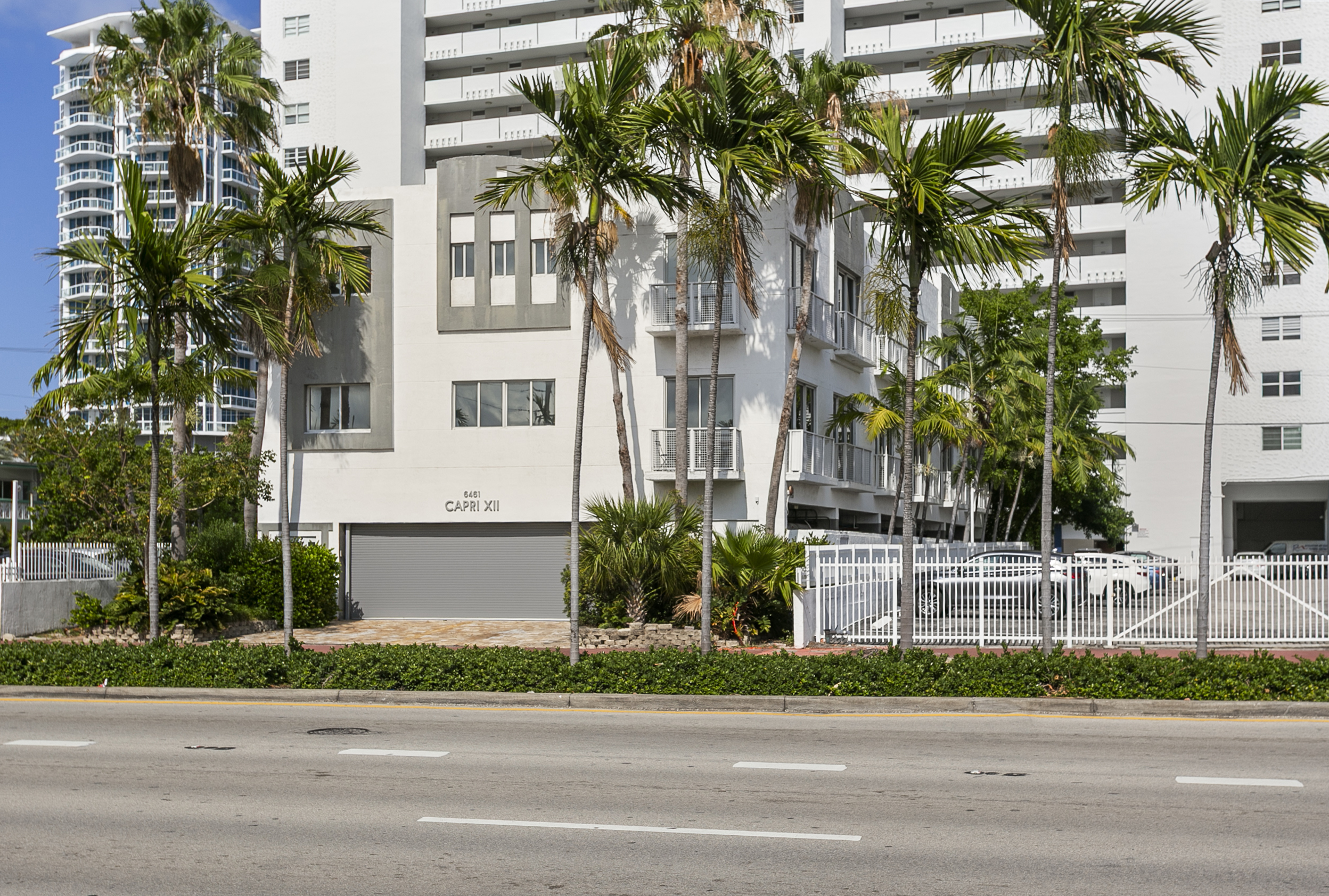 Small townhouse building in classic Miami white with grey accents, framed by palms