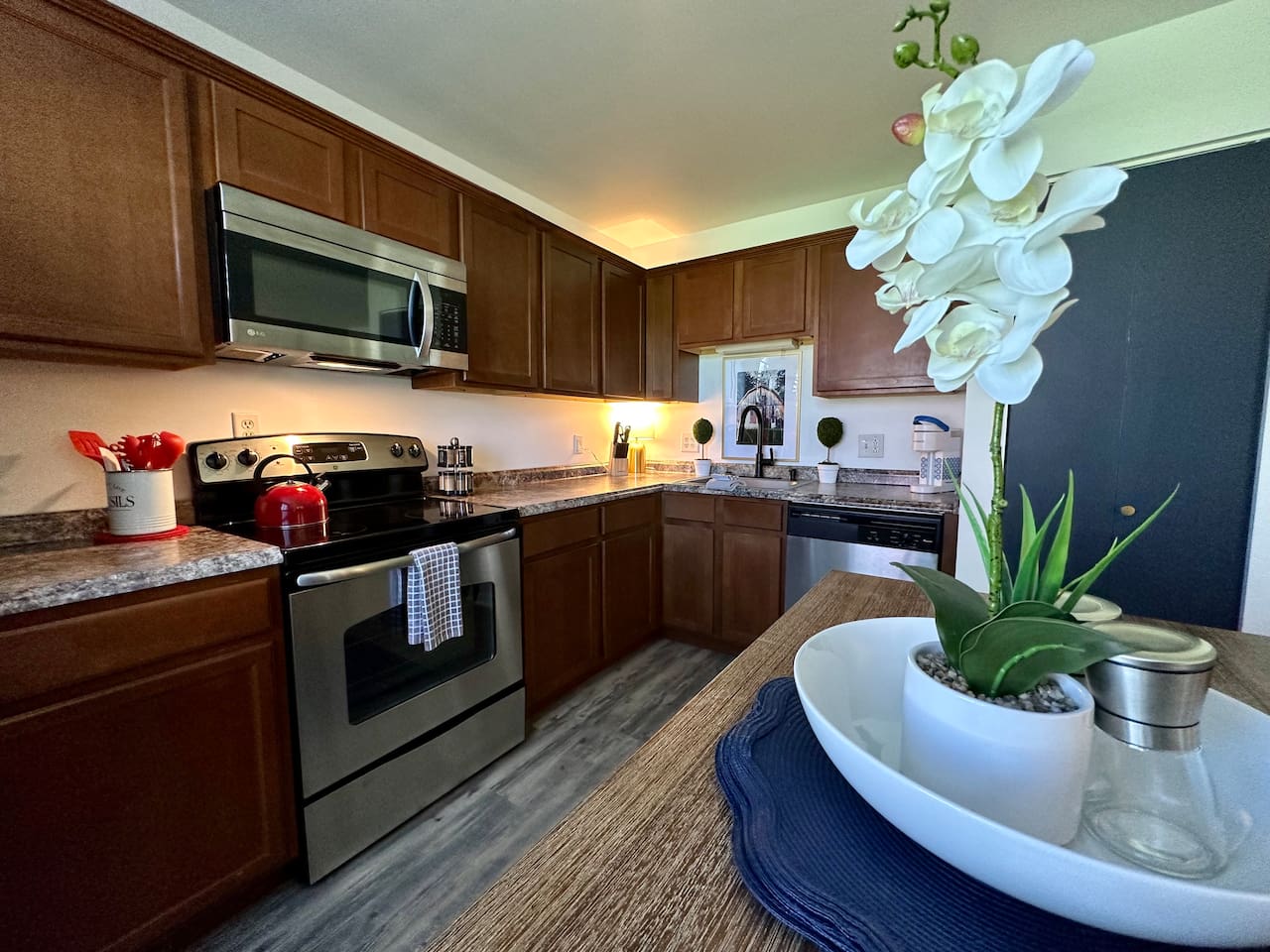 Modern kitchen with stainless steel appliances, spacious counters, and thoughtful details—like a central dining table with decor and essentials. Whether cooking, snacking, or gathering, this space is both functional and inviting for any stay.