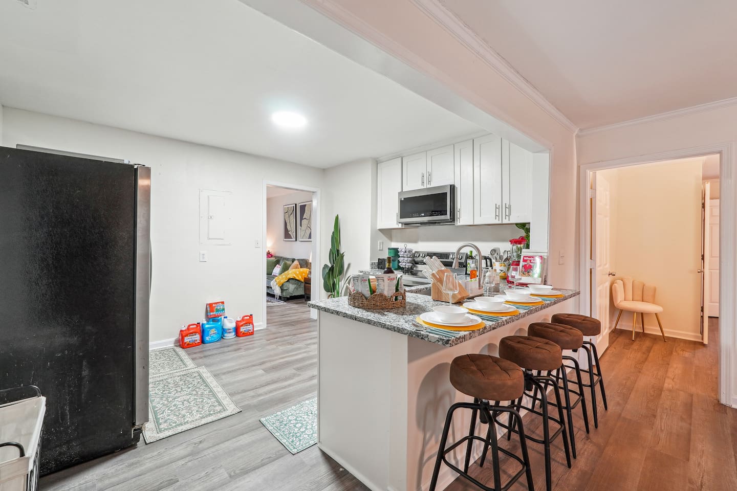 A fully equipped kitchen with a refrigerator, microwave, stove, oven,fridge, dishwasher, coffee maker, kettle, toaster, and blender. Includes plates, bowls, utensils, pots, and pans, plus four bar chairs for casual dining or socializing.

