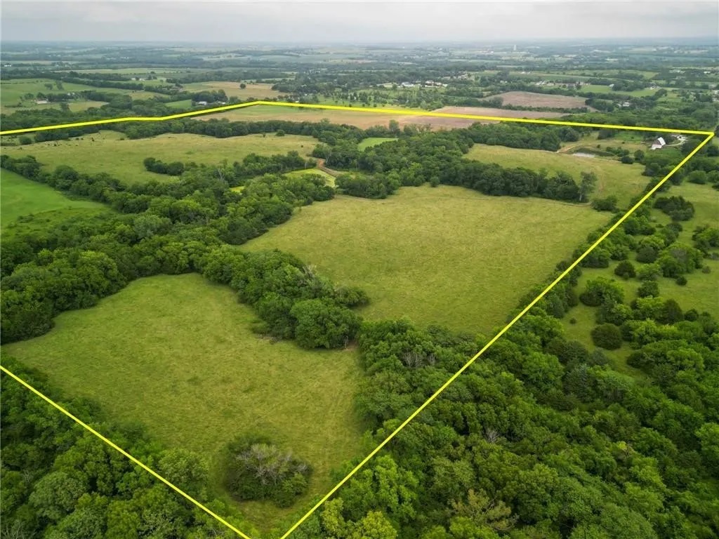 This aerial image outlines the property boundaries, highlighting the open fields, wooded areas, and peaceful setting that surround the farmhouse.