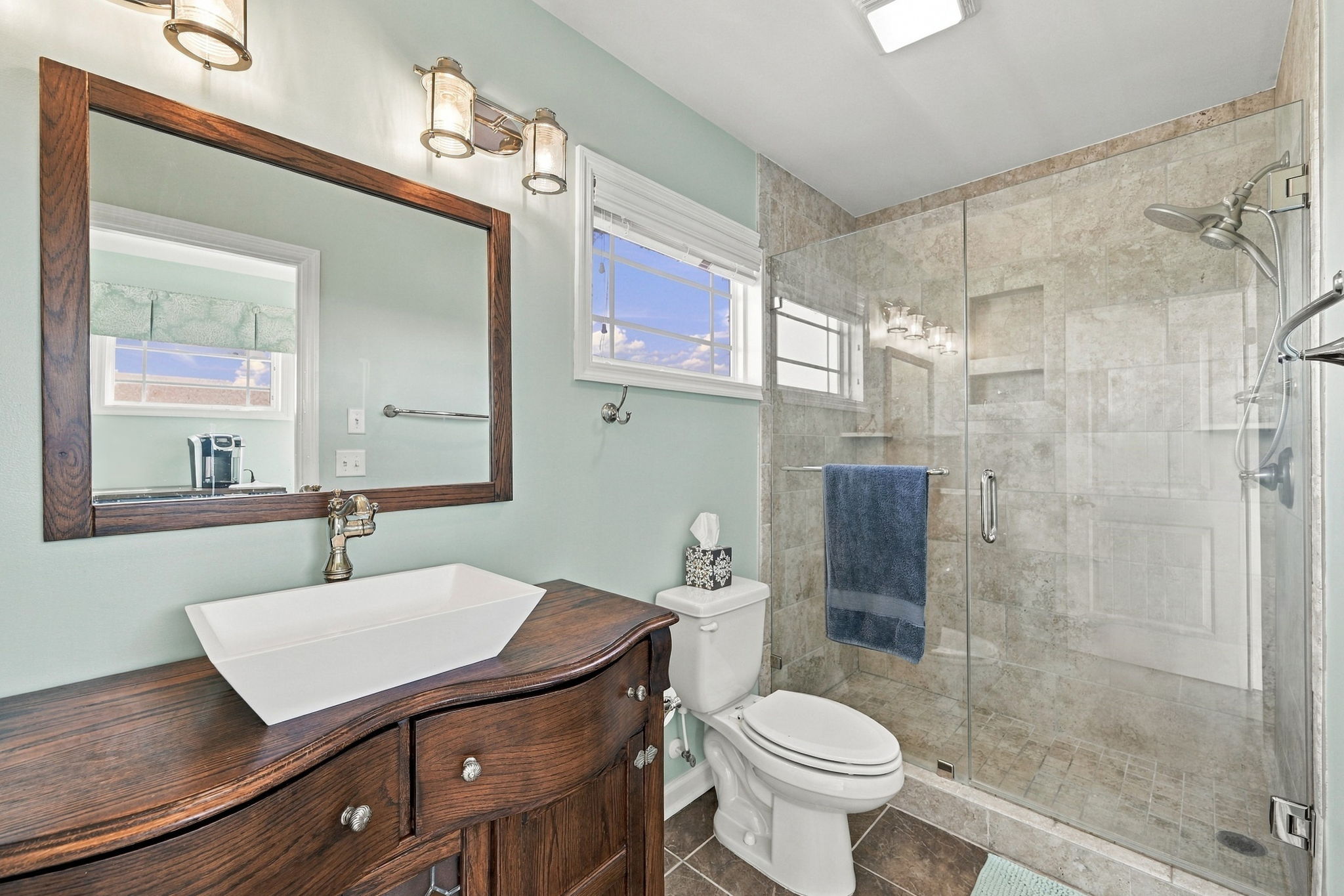 Beautifully appointed bathroom featuring a modern vessel sink, rustic wood vanity, and spacious tiled walk-in shower