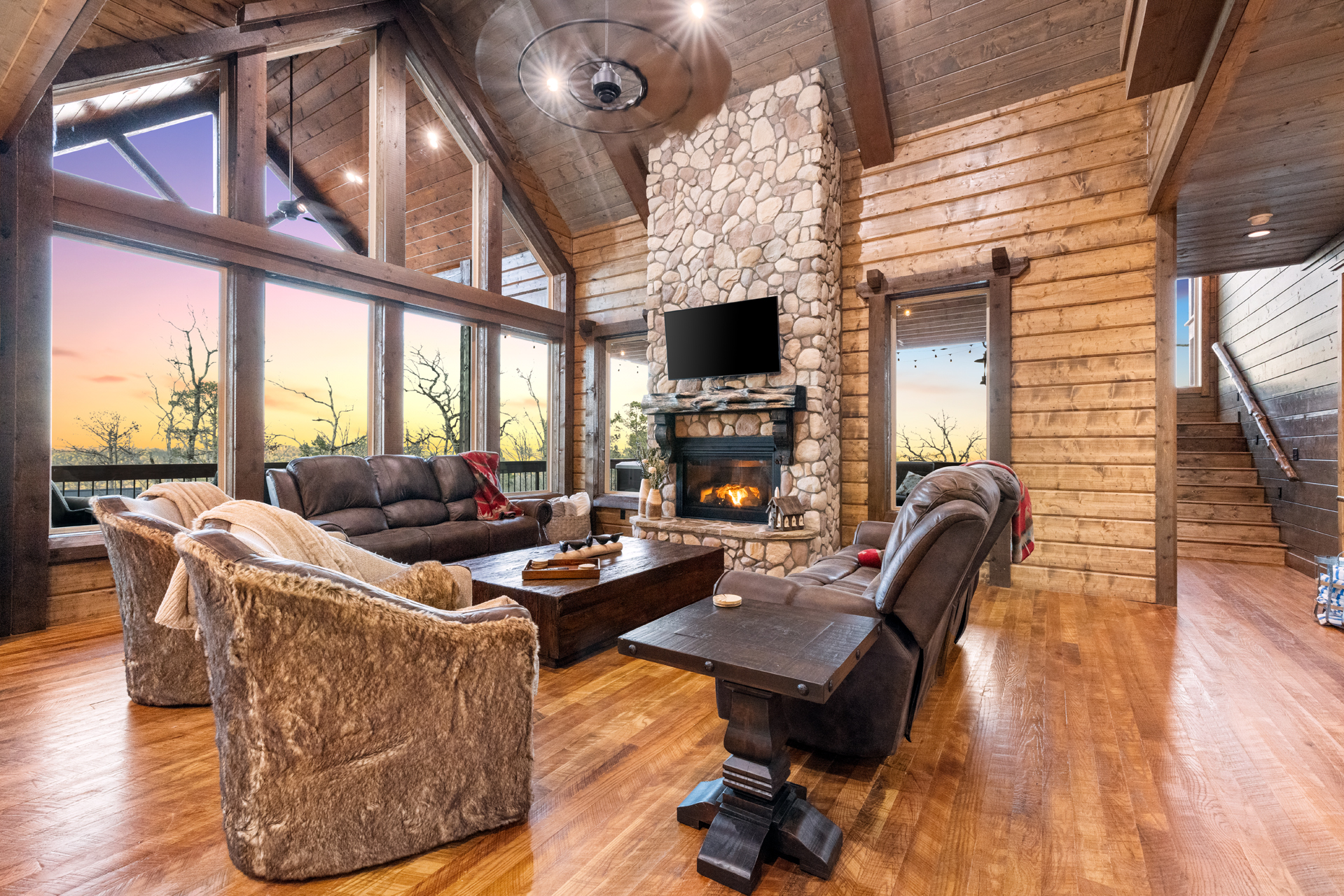 Spacious great room with soaring ceilings, stone fireplace, and panoramic windows