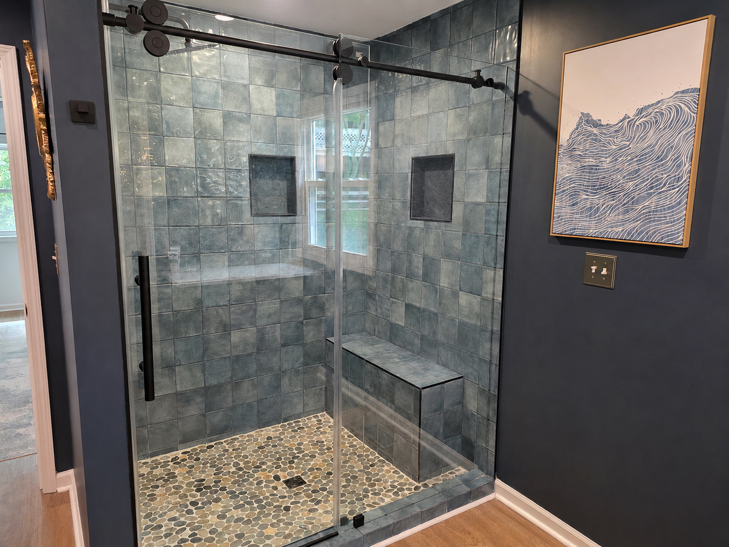 Walk-in tile shower in the main-floor primary bath with glass doors, bench seating and a clean spa-style feel.